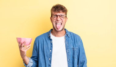 Genç ve yakışıklı bir adam tiksinmiş ve sinirlenmiş hissediyor ve dilini dışarı çıkarıyor. boş kase kavramı