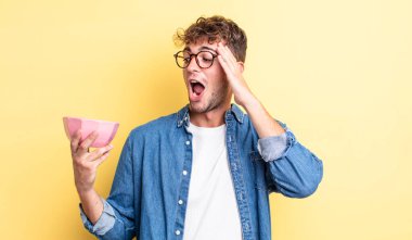 Genç yakışıklı adam mutlu, heyecanlı ve şaşırmış hissediyor. boş kase kavramı