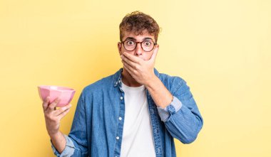 Genç ve yakışıklı bir adam elleri ile ağzını kapatıyor ve şok geçiriyor. boş kase kavramı