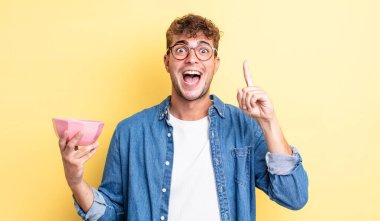 Genç yakışıklı bir adam bir fikri fark ettikten sonra mutlu ve heyecanlı bir dahi gibi hissediyor. boş kase kavramı