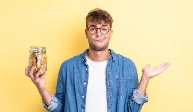 Genç yakışıklı adam şaşkın, şaşkın ve şüpheci hissediyor. kurabiye şişesi konsepti