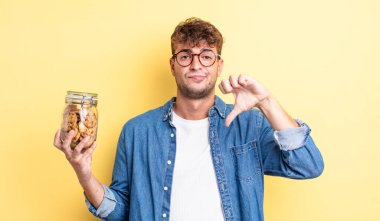 Genç ve yakışıklı bir adam kendini kötü hissediyor, baş parmağını kaldırıyor. kurabiye şişesi konsepti