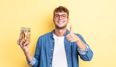 Genç ve yakışıklı bir adam gururlu, olumlu gülümsüyor. kurabiye şişesi konsepti