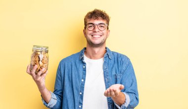 Genç ve yakışıklı bir adam arkadaşça gülümsüyor ve bir konsept sunuyor. kurabiye şişesi konsepti