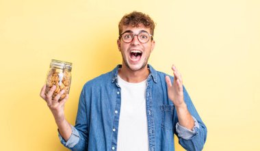 Genç yakışıklı adam kendini mutlu hissediyor ve inanılmaz bir şeye hayret ediyor. kurabiye şişesi konsepti