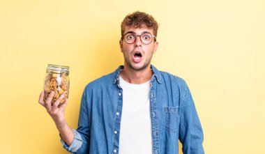 Genç ve yakışıklı bir adam çok şaşırmış ya da şaşkın görünüyor. kurabiye şişesi konsepti