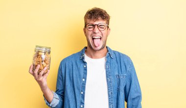 Genç, yakışıklı, neşeli ve asi tavırlı, şaka yapan ve dilini dışarı çıkaran bir adam. kurabiye şişesi konsepti