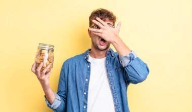 Genç, yakışıklı adam şok olmuş, korkmuş ya da korkmuş görünüyor. kurabiye şişesi konsepti