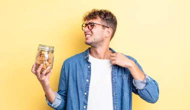 Genç ve yakışıklı adam stresli, endişeli, yorgun ve hayal kırıklığına uğramış hissediyor. kurabiye şişesi konsepti