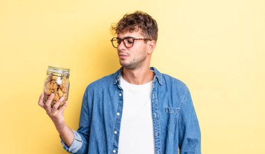 Genç ve yakışıklı bir adam üzgün, üzgün ya da kızgın hissediyor ve yan tarafa bakıyor. kurabiye şişesi konsepti