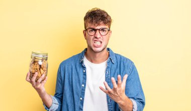 Genç ve yakışıklı bir adam sinirli, sinirli ve sinirli görünüyor. kurabiye şişesi konsepti