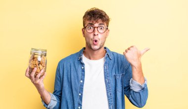 İnanamadığı için şaşırmış genç ve yakışıklı bir adam. kurabiye şişesi konsepti