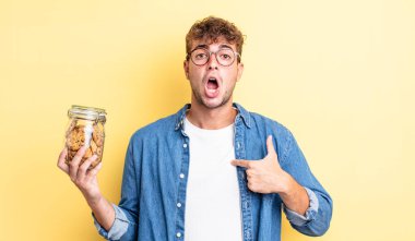 Şok olmuş ve ağzı açık, kendini işaret eden genç ve yakışıklı bir adam. kurabiye şişesi konsepti