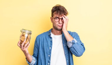 Genç yakışıklı bir adam bıkkın, hayal kırıklığına uğramış ve yorucu bir geceden sonra uykulu hissediyor. kurabiye şişesi konsepti