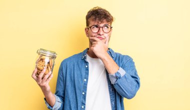 Genç yakışıklı düşünen, kuşkulu ve kafası karışık bir adam. kurabiye şişesi konsepti