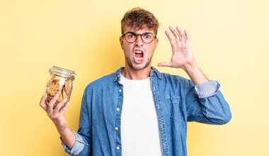 Genç yakışıklı adam ellerini havaya kaldırarak çığlık atıyor. kurabiye şişesi konsepti