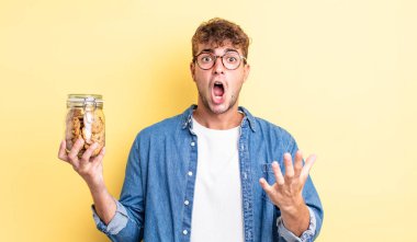 Genç ve yakışıklı bir adam şok olmuş ve şaşırmış hissediyor. kurabiye şişesi konsepti