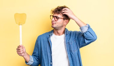 Kafası karışmış, kafası karışmış, kaşınan genç, yakışıklı bir adam. Sineklik konsepti