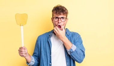 Ağzı ve gözleri açık ve eli çenesinde genç yakışıklı bir adam. Sineklik konsepti