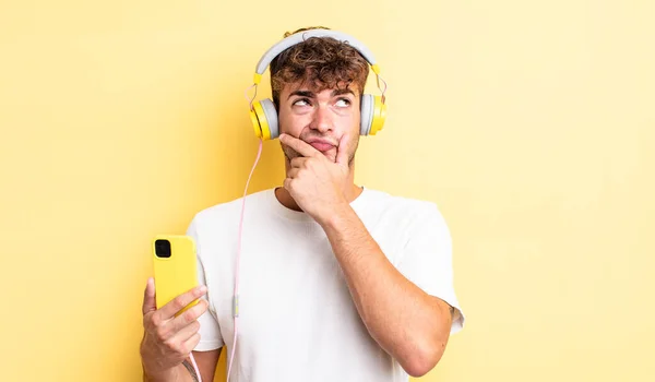 Jonge Knappe Man Denkend Twijfelachtig Verward Koptelefoon Smartphone Concept — Stockfoto