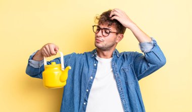 Genç yakışıklı adam mutlu bir şekilde gülümsüyor ve hayal kuruyor veya şüphe ediyor. Çaydanlık konsepti