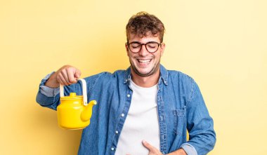 Genç yakışıklı bir adam komik bir şakaya gülüyor. Çaydanlık konsepti.