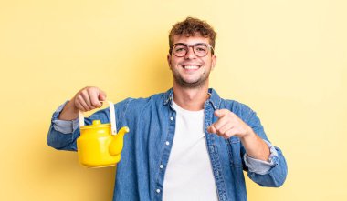 Genç yakışıklı adam kamerayı göstererek seni seçiyor. Çaydanlık konsepti.