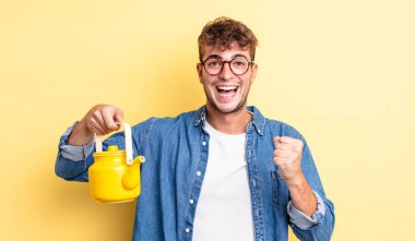 Genç yakışıklı adam şokta, gülüyor ve başarılı çaydanlık konseptini kutluyor.