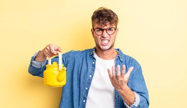 Genç yakışıklı adam sinirli, sinirli ve meyveli çaydanlık konsepti.