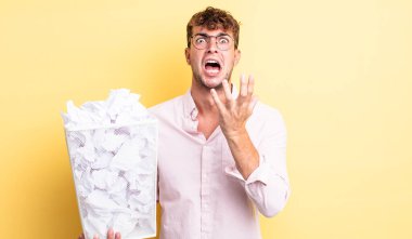 Genç yakışıklı adam umutsuz, sinirli ve stresli görünüyor. kağıt toplar çöp konsepti