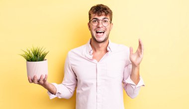 Genç yakışıklı adam kendini mutlu hissediyor ve inanılmaz bir şeye hayret ediyor. dekoratif bitki konsepti