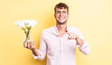 Genç ve yakışıklı bir adam kamerayı işaret ederek seni seçiyor. çiçek konsepti