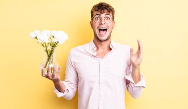 Genç yakışıklı adam kendini mutlu hissediyor ve inanılmaz bir şeye hayret ediyor. çiçek konsepti