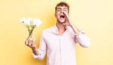 Genç yakışıklı adam mutlu hissediyor, elleri ağzının kenarında bağırıyor. çiçek konsepti