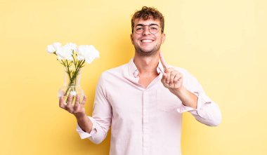 Genç yakışıklı adam gururla gülümsüyor ve kendinden emin bir numara oluyor. çiçek konsepti