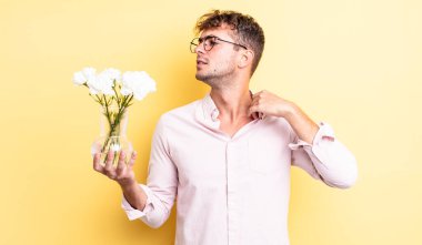 Genç ve yakışıklı adam stresli, endişeli, yorgun ve hayal kırıklığına uğramış hissediyor. çiçek konsepti