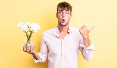 İnanamadığı için şaşırmış genç ve yakışıklı bir adam. çiçek konsepti