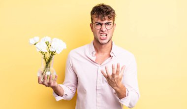 Genç ve yakışıklı bir adam sinirli, sinirli ve sinirli görünüyor. çiçek konsepti