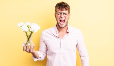 Genç yakışıklı adam agresif bir şekilde bağırıyor, çok kızgın görünüyor. çiçek konsepti