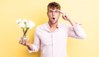 Genç yakışıklı adam şaşırmış görünüyor, yeni bir düşünce, fikir ya da konsept fark ediyor. çiçek konsepti
