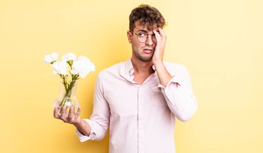 Genç yakışıklı bir adam bıkkın, hayal kırıklığına uğramış ve yorucu bir geceden sonra uykulu hissediyor. çiçek konsepti