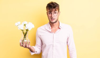 Genç yakışıklı adam şaşkın ve şaşkın hissediyor. çiçek konsepti