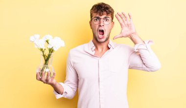 Genç yakışıklı adam ellerini havaya kaldırarak çığlık atıyor. çiçek konsepti