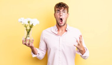 Genç ve yakışıklı bir adam şok olmuş ve şaşırmış hissediyor. çiçek konsepti