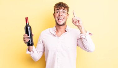 Genç yakışıklı bir adam bir fikri fark ettikten sonra mutlu ve heyecanlı bir dahi gibi hissediyor. şarap şişesi konsepti