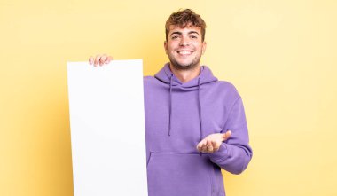 Genç ve yakışıklı bir adam arkadaşça gülümsüyor ve bir konsept sunuyor. boşluk konseptini kopyala