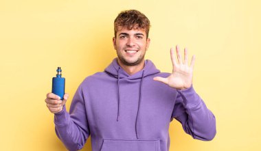 Genç yakışıklı adam gülümsüyor ve arkadaş canlısı görünüyor, beş numarayı gösteriyor. buharlaştırıcı kavramı