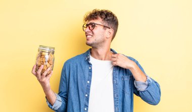 Genç ve yakışıklı adam stresli, endişeli, yorgun ve hayal kırıklığına uğramış hissediyor. kurabiye şişesi konsepti