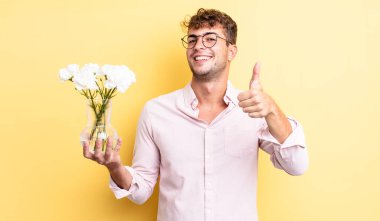 Genç ve yakışıklı bir adam gururlu, olumlu gülümsüyor. çiçek konsepti