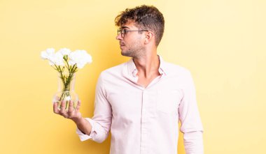 Profilde genç yakışıklı bir adam hayal kuruyor, hayal kuruyor ya da hayal kuruyor. çiçek konsepti